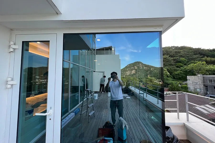 모던한 백색 외관의 2층 주택, 큰 통유리 창과 테라스가 있는 전경