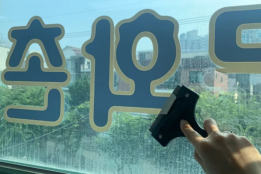 시공을 마친 창문 너머로 나무와 하늘이 비치는 전경