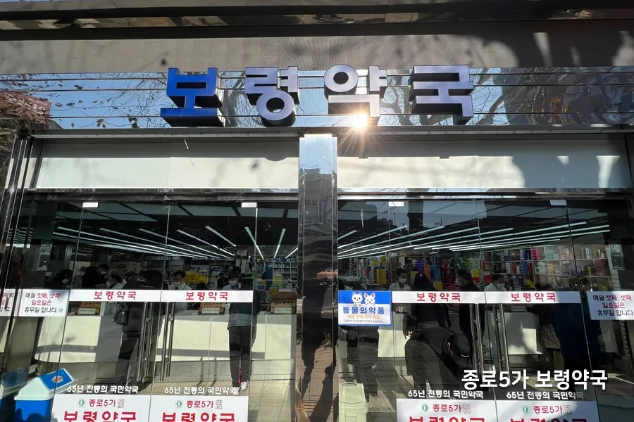 약국 진열장 유리, 정리된 약품과 판매대가 비치는 모습