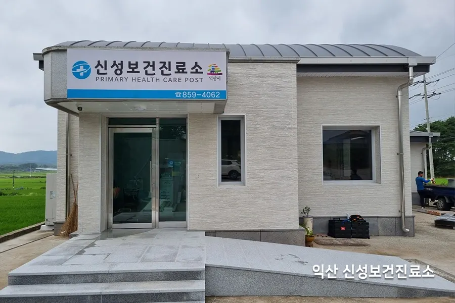 직원 안내 게시물과 모니터가 있는 사무 공간, 창밖으로 주차된 차량이 보이는 모습